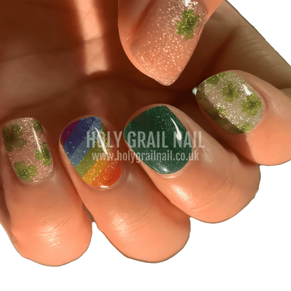 Close up of St Patrick's Day gel nails with glitter shamrocks and rainbow designs