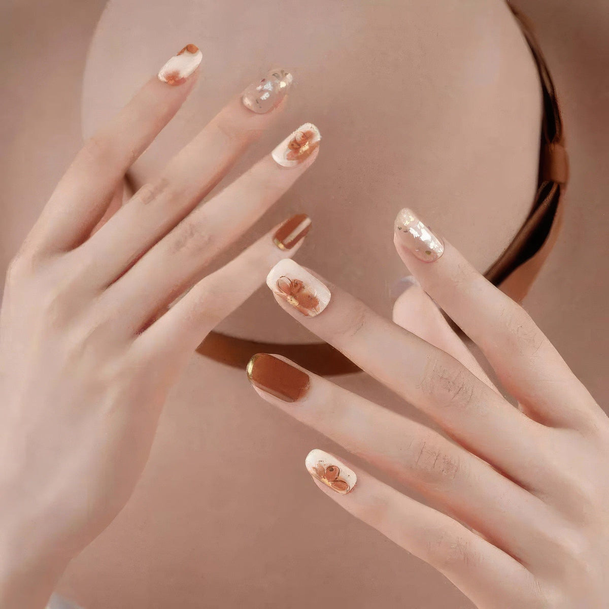 Brown and nude gel nail wraps with crystal patterns applied on manicured hands