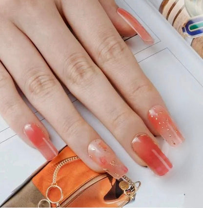 Glossy coral gel nail wraps on hand showing warm pink tones for elegant manicure