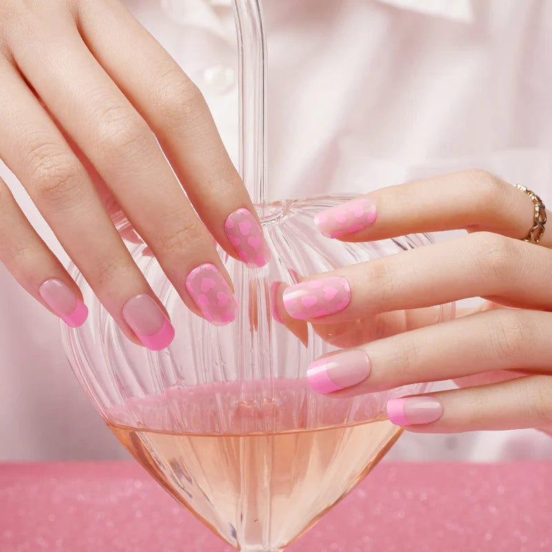 Pink gel nail wraps on hands holding diamond-shaped glass vessel