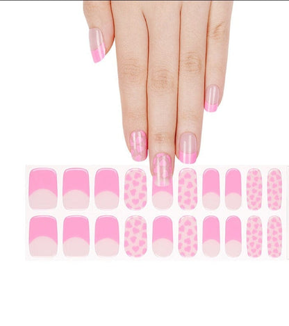 Hand wearing pink gel nail wraps with heart patterns and French tips