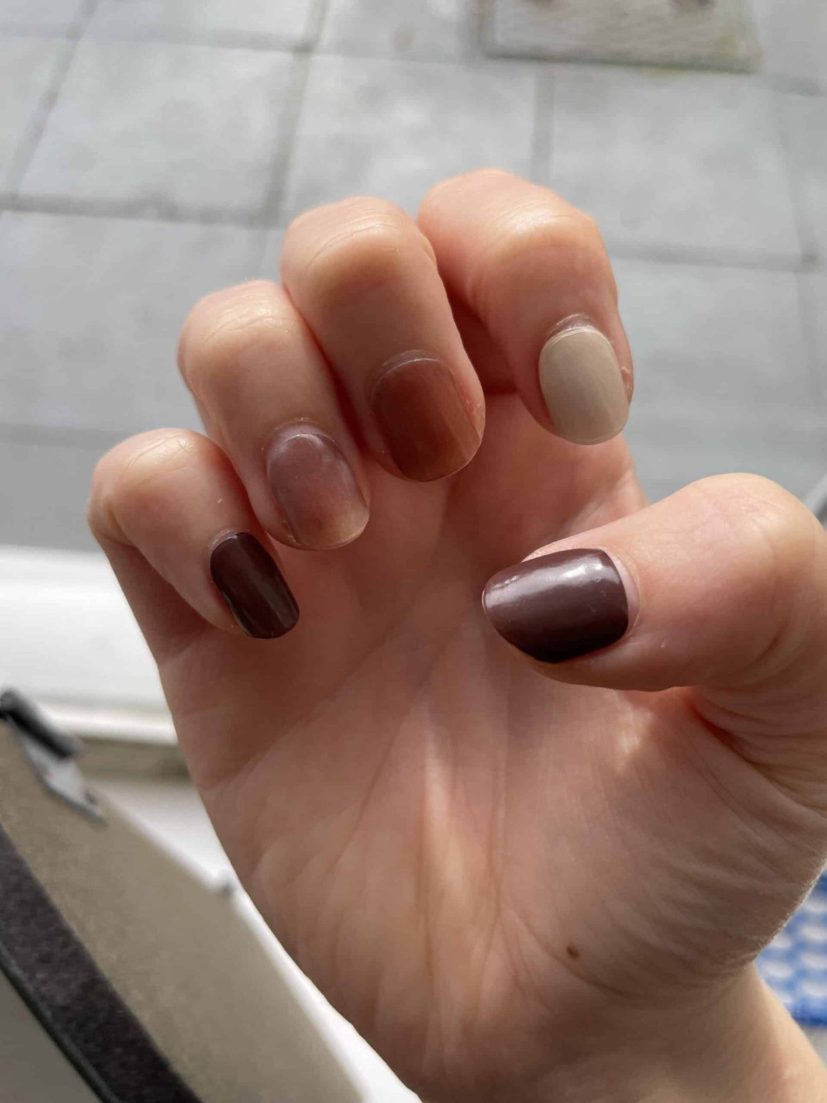 Hand wearing neutral brown gel nail wraps in mixed autumn shades manicure