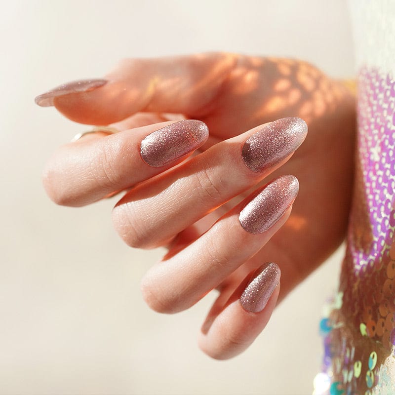 Hand displaying rose gold sparkly gel nail wraps with shimmery glitter finish