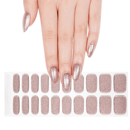 Hand with rose gold gel nail wraps beside full sheet of glitter nail art wraps