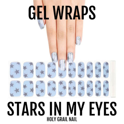 Light blue gel nail wraps with silver star pattern displayed on hand manicure