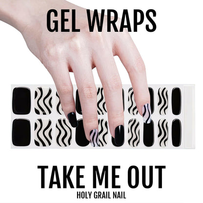 Hand positioned over black and white diagonal striped gel nail wraps sheet