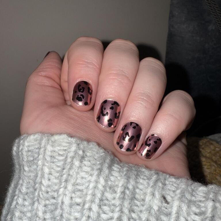 Rose gold leopard print gel nail wraps on hand showing chrome animal pattern manicure
