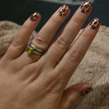 Hand wearing pink leopard print gel nails with black spots animal print