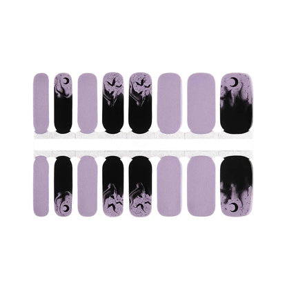 Lilac nail wraps with black smoke, crescent moons, and bat silhouette accents